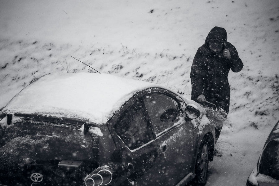 Driver stranded in a snowstorm next to a car that will not start