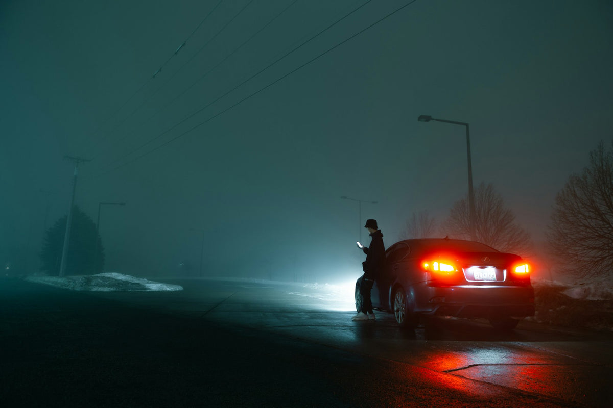 Driver stranded next to a broken down car at night